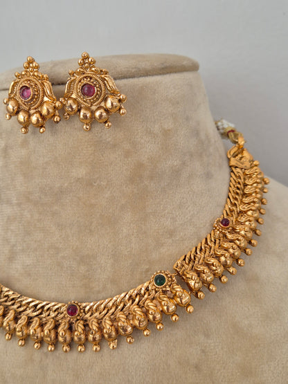 Traditional Indian antique-finish brass necklace set showcasing elaborate textured ridge motifs, small colorful gemstone embellishments, and delicate hanging gold beads from the Naitri Golden Jewellery collection by naitri.in