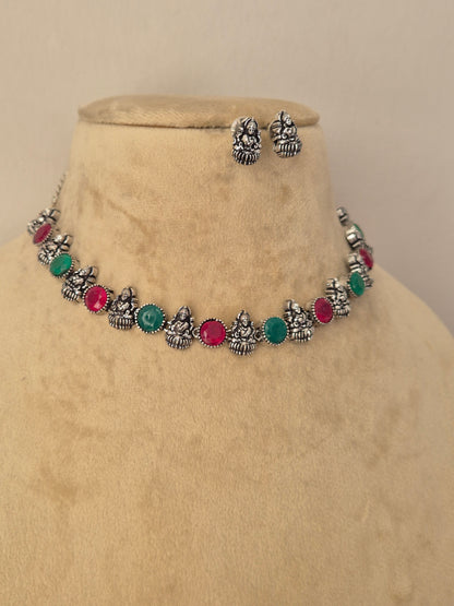 A silver-toned jewelry set featuring a necklace and matching earrings with small metallic motifs and round green and pink stones by naitri