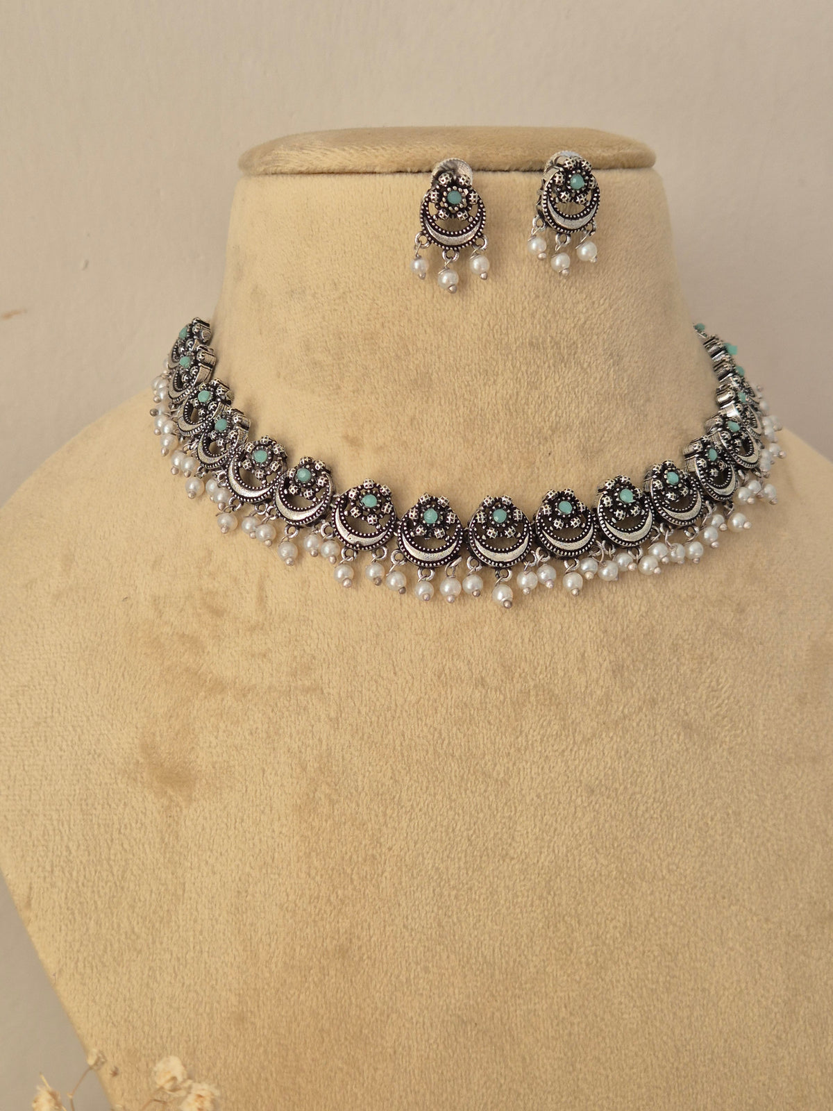 Oxidized silver choker necklace with green stone inlay and pearl drop details, paired with matching stud earrings by naitri.in