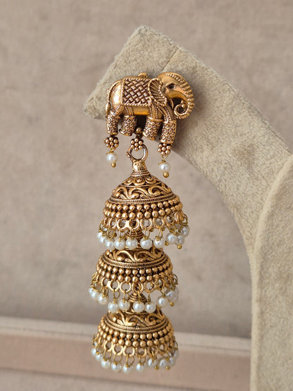 Gold-toned drop dangle earrings with intricate carved deity motifs, stone embellishments, and hanging pearl clusters by naitri.in