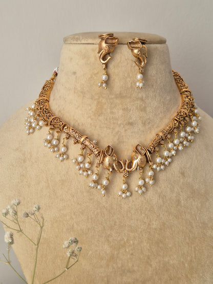 Intricate brass alloy gold-plated choker necklace with hanging pearl detailsgold imitation jewelry strand necklace and small pearl drop earrings by naitri.in