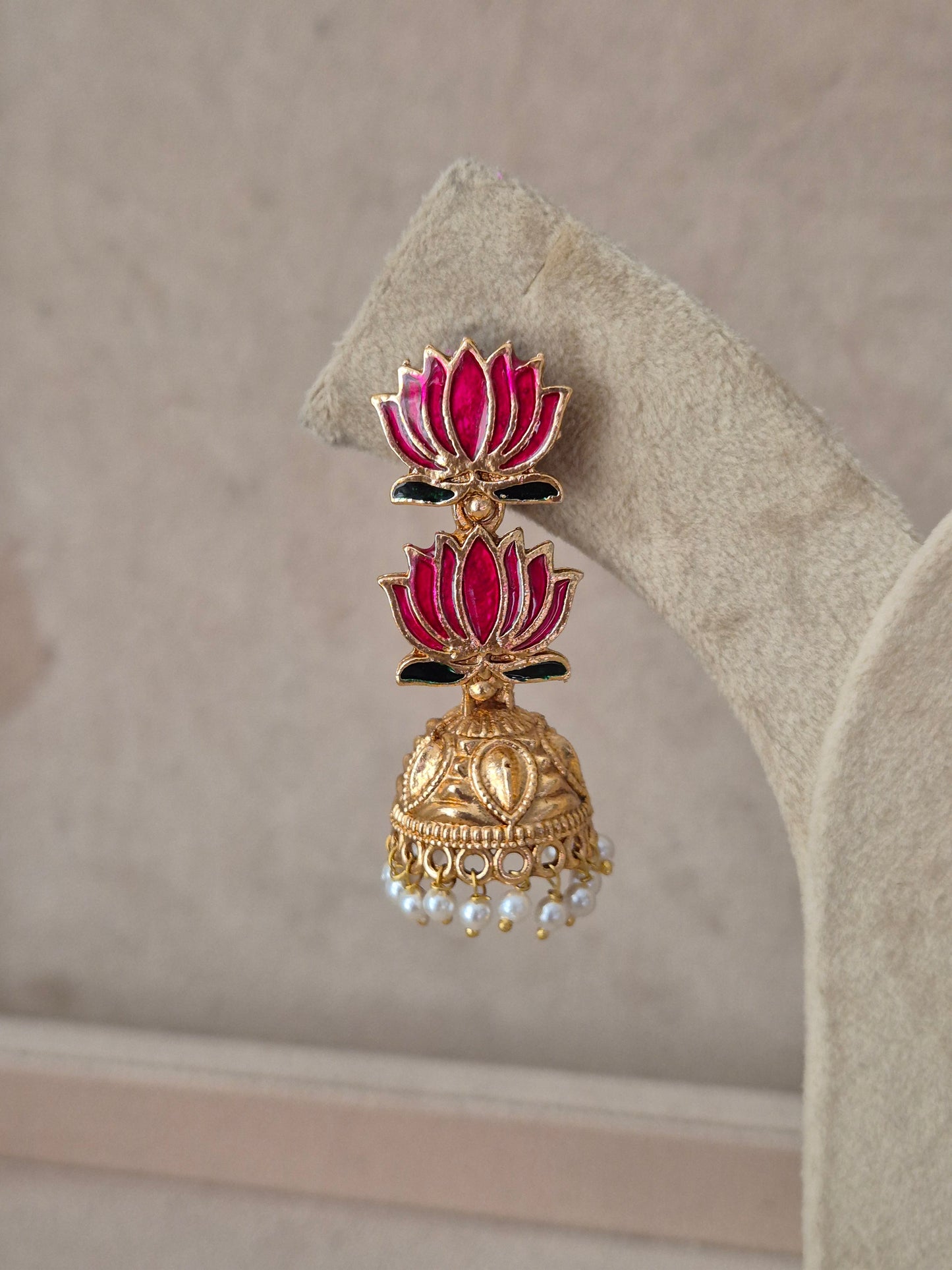 A pair of traditional Indian jhumka earrings with gold-plated metalwork, pink enamel flower petals, and small white pearl-like beads, by naitri.in