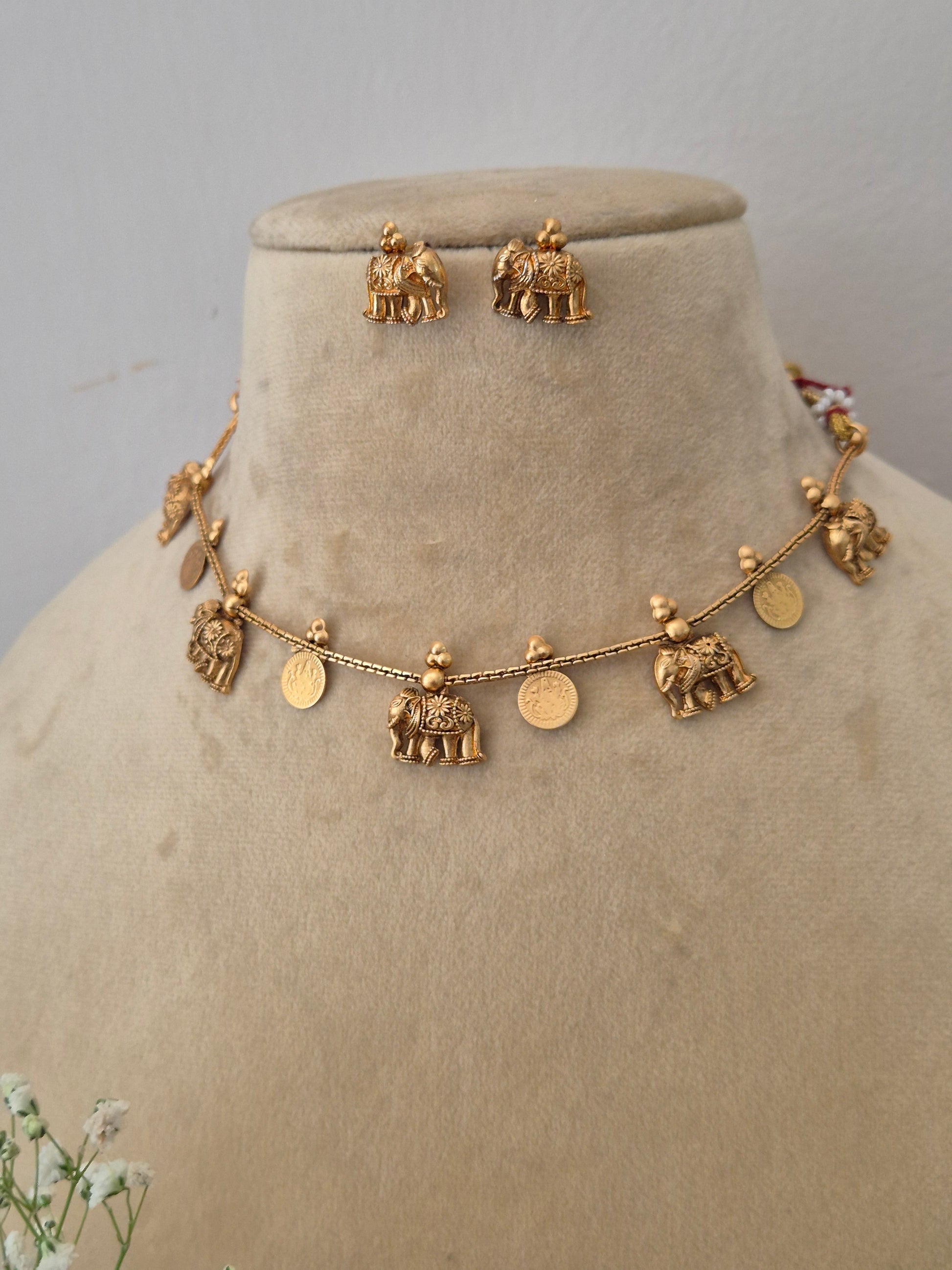 Modern Indian ethnic imitation jewelry set including a multi-charm golden brass alloy choker necklace and matching small jhumka earrings, by naitri.in