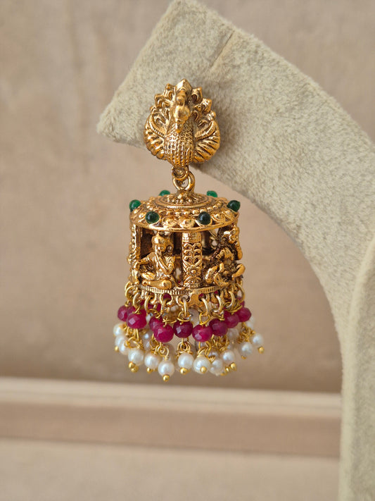 Close-up of Naitri Bhakti premium gold ethnic earrings showcasing traditional Indian temple jewelry craftsmanship with vibrant pink stone embellishments and delicate pearl bead fringe by naitri.in
