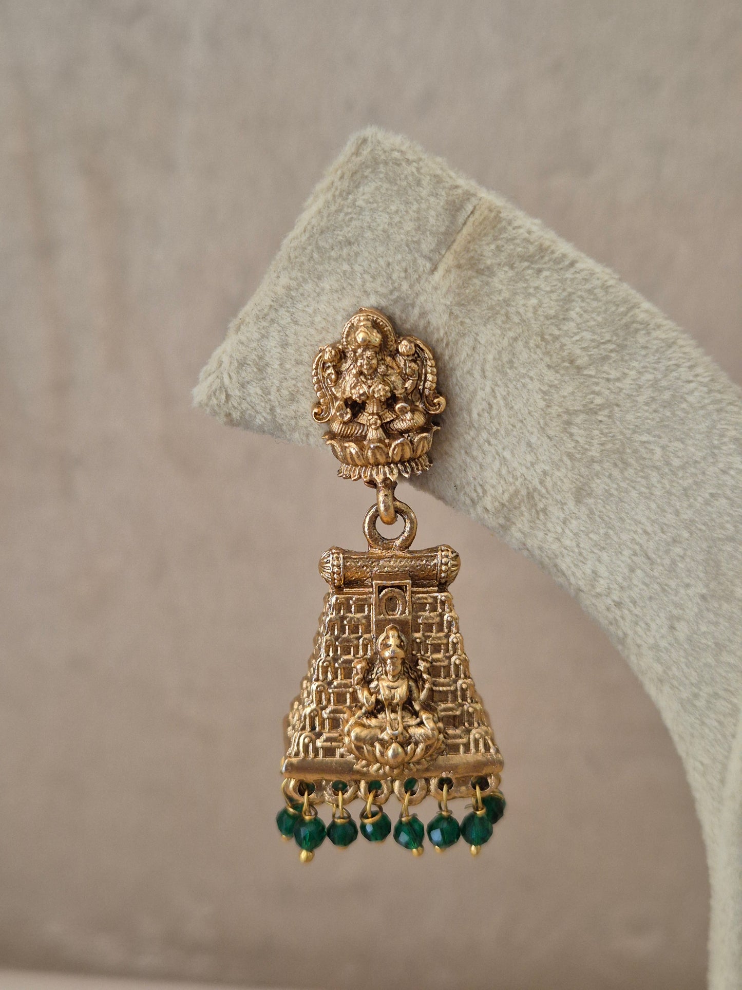 Close-up of Naitri Bhumika premium gold ethnic earrings showcasing traditional Indian temple architecture craftsmanship and vibrant green stone embellishments by naitri.in