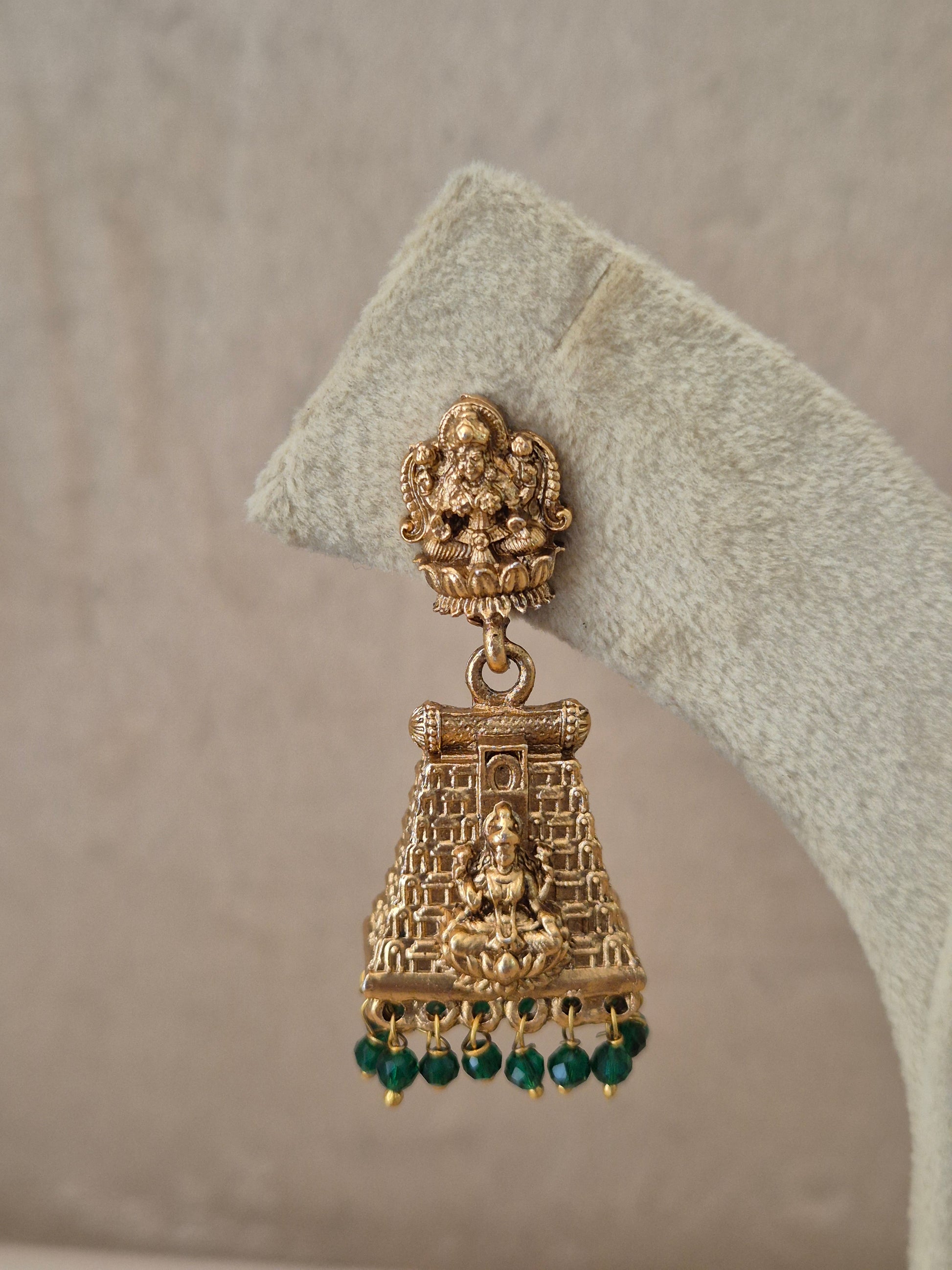 Close-up of Naitri Bhumika premium gold ethnic earrings showcasing traditional Indian temple architecture craftsmanship and vibrant green stone embellishments by naitri.in