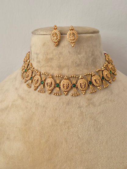 Ornate brass alloy choker set featuring intricate Indian artisanal engravings and small green gemstone accents, shown with matching stud earrings by naitri.in
