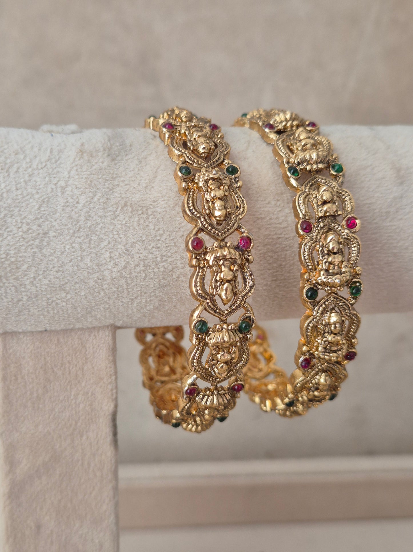 Two gold-toned traditional Indian bangles decorated with small red and green gemstones, by naitri.in