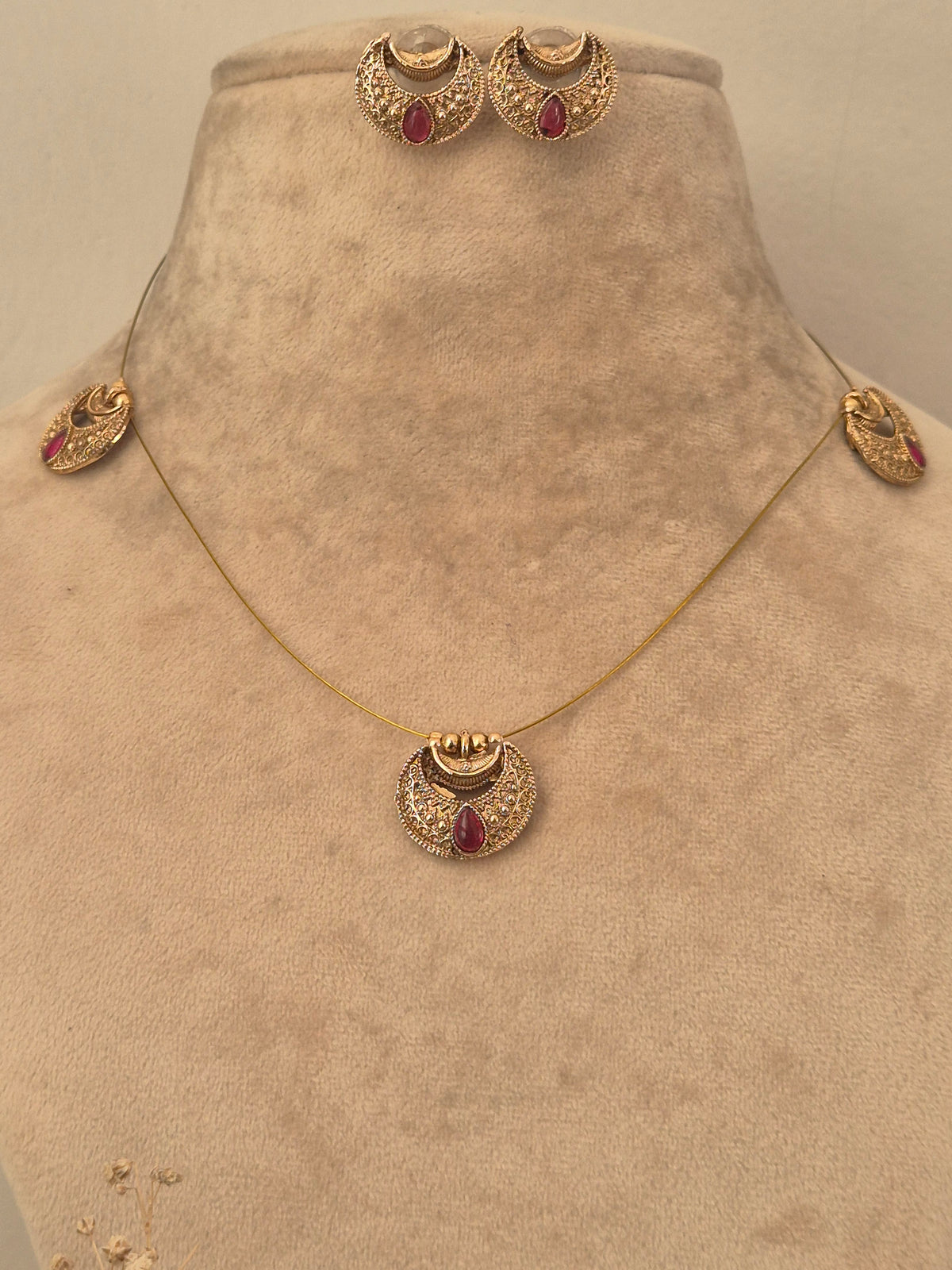 Gold invisible chain necklace set with red stone accents and matching stud earrings by naitri