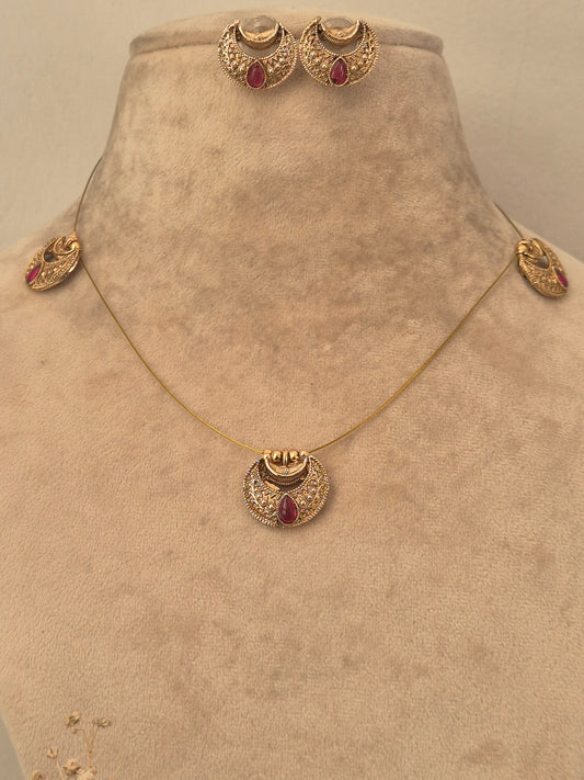 Gold invisible chain necklace set with red stone accents and matching stud earrings by naitri