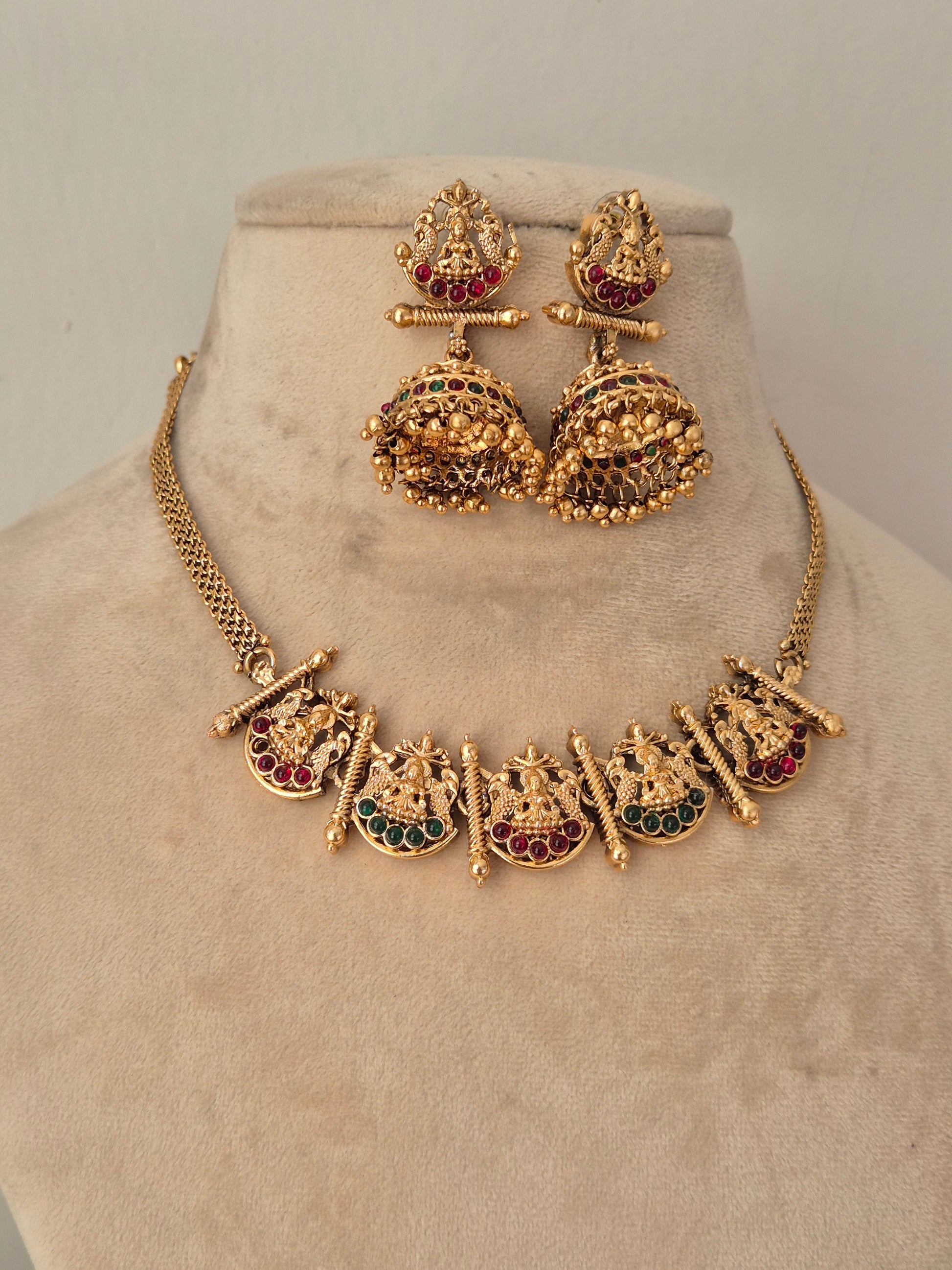 Gold-toned traditional jewelry set, including a necklace with deity motifs and matching earrings by naitri.in