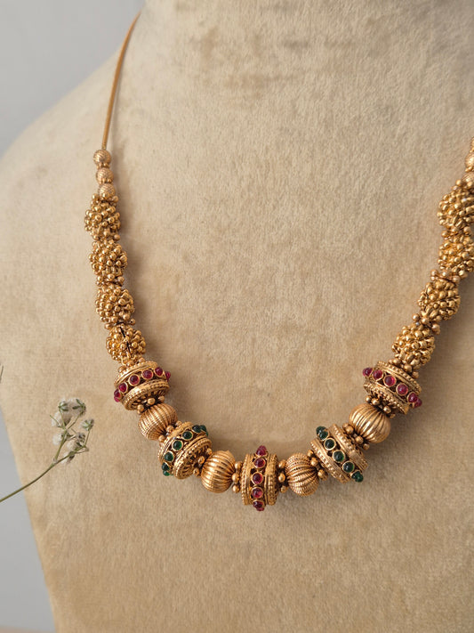 Traditional Devi necklace made from brass alloy with a polished golden finish, showcasing a snake chain design with textured gold spacers and ruby-red stone details by naitri.in