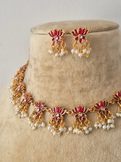 Gold-plated Indian ethnic choker set featuring a textured floral pattern with ruby-pink gemstone details and delicate dangling white pearls, by naitri.in