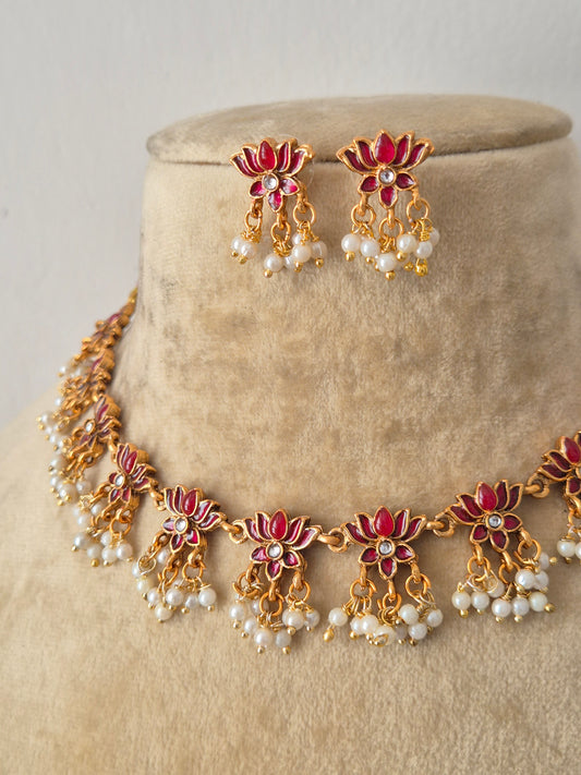 Gold-plated Indian ethnic choker set featuring a textured floral pattern with ruby-pink gemstone details and delicate dangling white pearls, by naitri.in