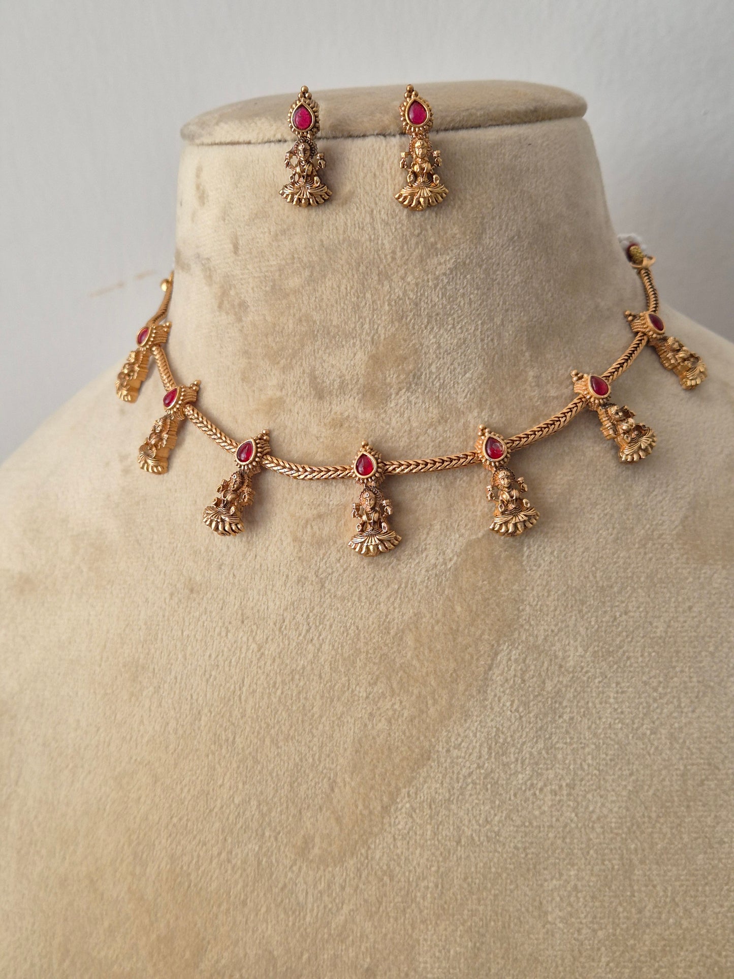Antique gold-plated ethnic choker set featuring delicate dangling pendants with tiny ruby-red stone accents with coordinating hanging stud earrings by naitri.in