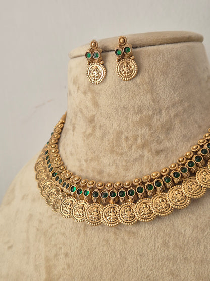 Gold-toned traditional jewelry set featuring a choker necklace and matching drop earrings, embellished with circular coin motifs and small green stone accents, by naitri.in
