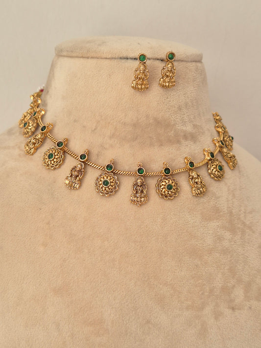 Gold-toned traditional jewelry set including a necklace with small deity-shaped charms and green stone accents, plus matching earrings by naitri.in