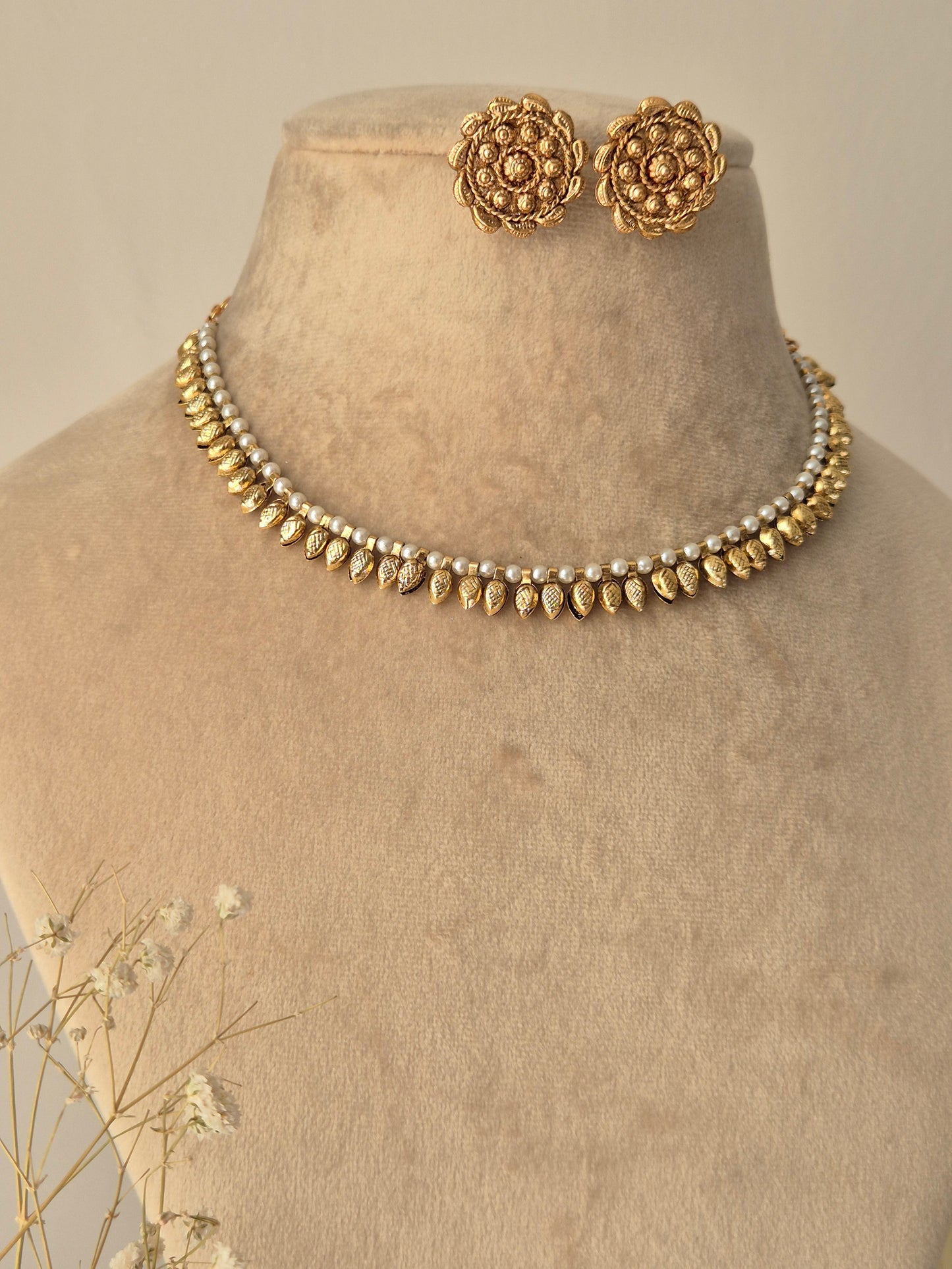 Gold necklace with small pearls attached making chain and small leaf s between every pearls and  small tear shaped design attached out side earring making petals by naitri.in