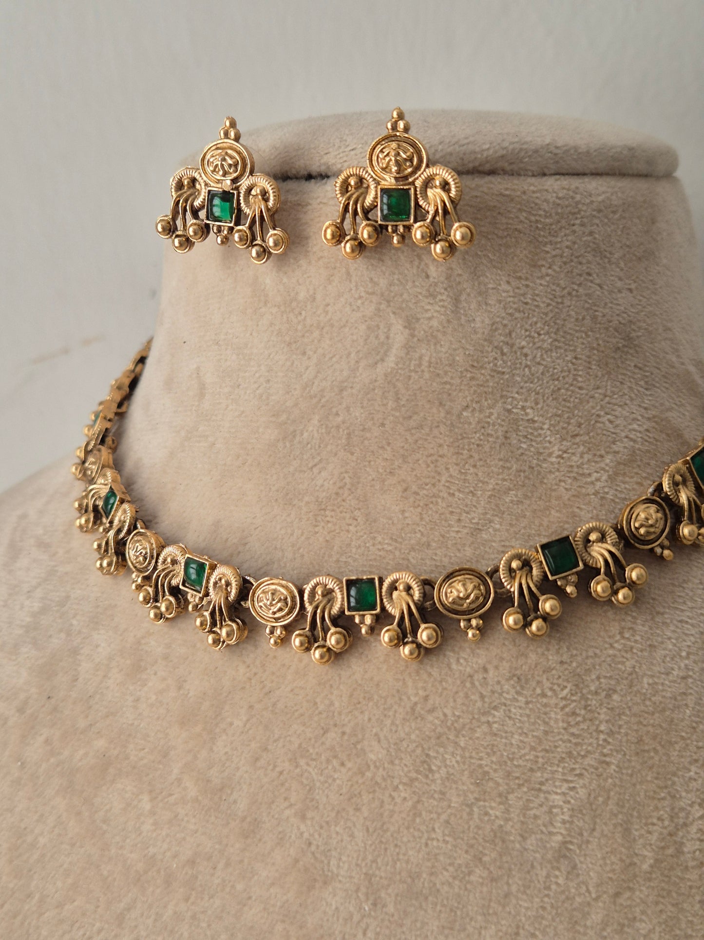 Gold-toned traditional jewelry set featuring a necklace and matching earrings with green square and round stones, by naitri.in