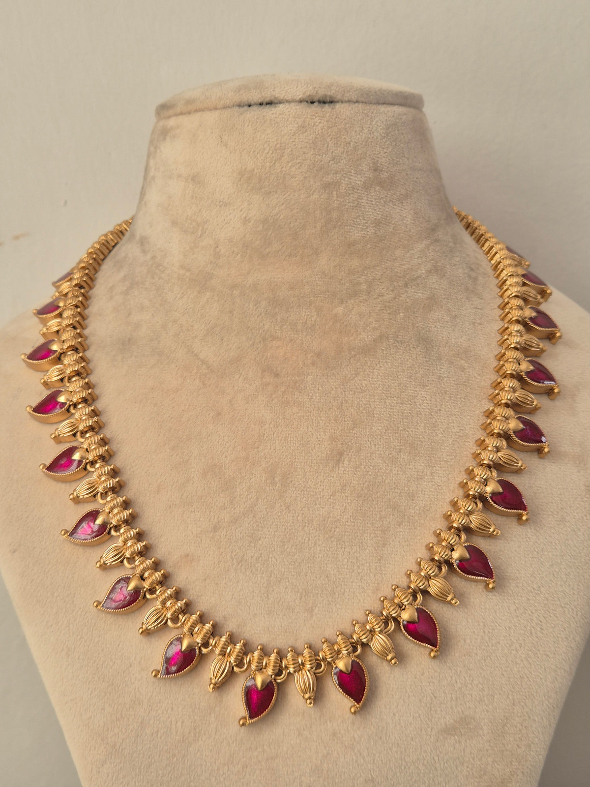 Traditional gold necklace featuring teardrop ruby red stone clusters with intricate antique embellishments, by naitri.in