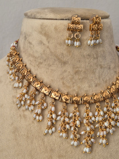 Traditional Indian gold-toned choker necklace set featuring intricate metalwork and cascading white pearl droplets by naitri.in