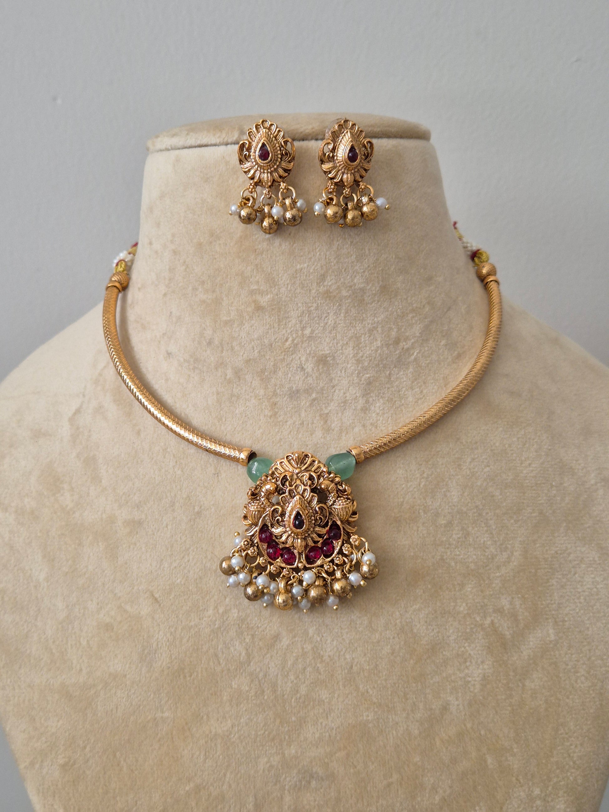 Traditional gold temple necklace set with pink and green stones and pearl droplets, including matching jhumka earrings by naitri.in