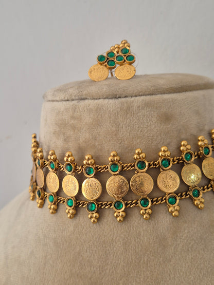 Modern Indian imitation jewelry set featuring an intricate golden brass alloy coin choker necklace with emerald-green gemstone accents, by naitri.in
