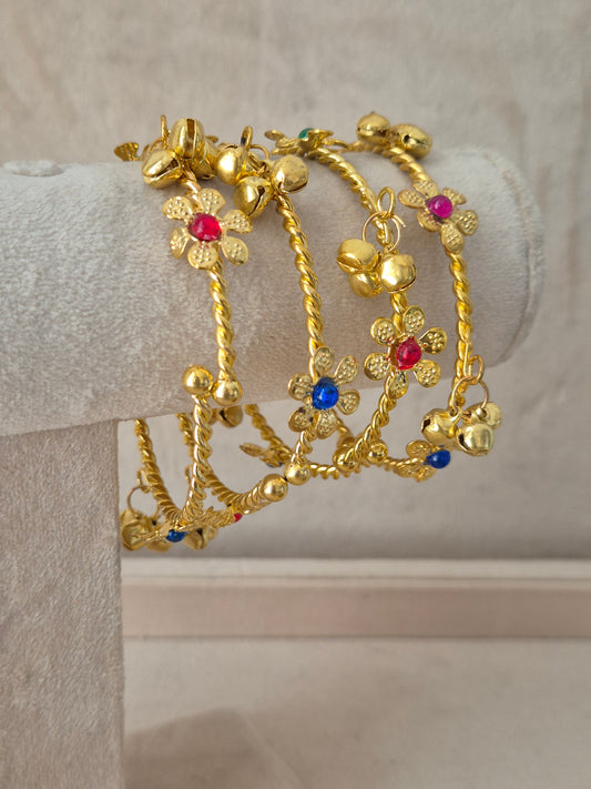 Close-up of Naitri Geetanjali premium gold ethnic bangles showcasing traditional Indian floral craftsmanship with colorful gemstone accents and elegant hanging latkan charms by naitri.in