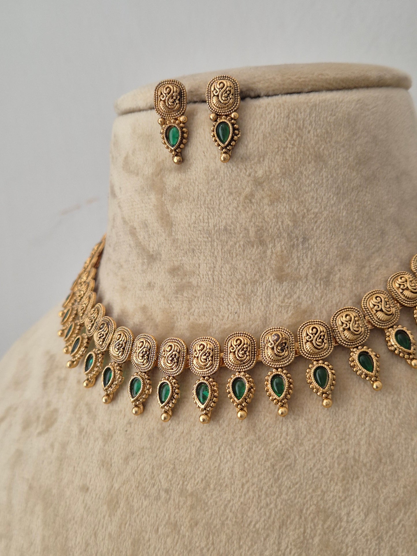Gold-toned traditional jewelry set featuring a necklace and matching earrings with green teardrop-shaped stones, by naitri.in