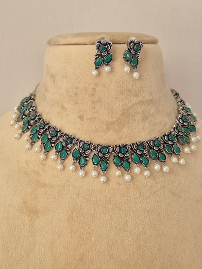Pair of oxidized silver floral motif choker necklace with matching green stone earrings  by Naitri
