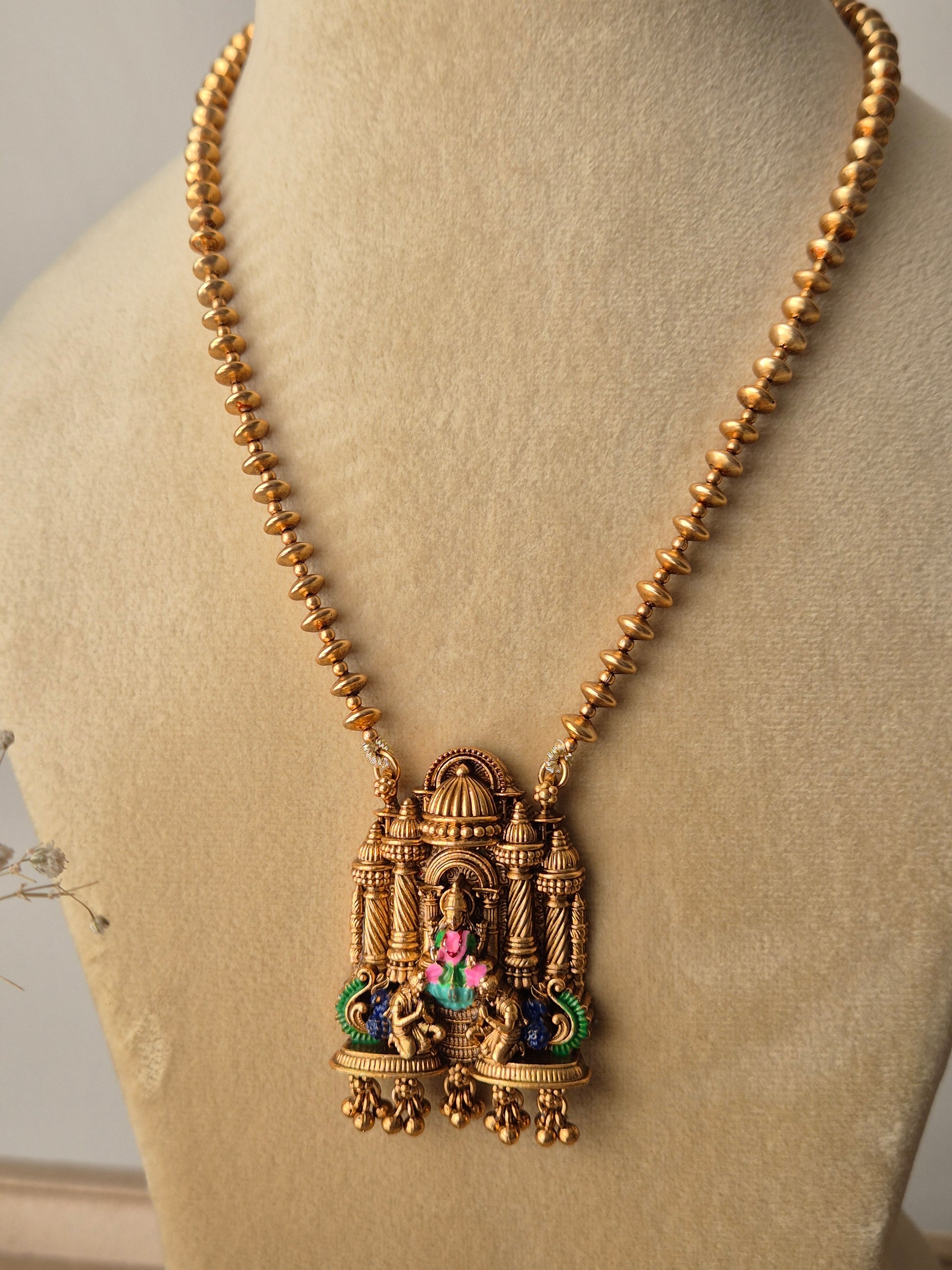 Handcrafted Devanshi temple necklace set in golden brass with intricate deity carvings and multicolored stone embellishments by naitri.in
