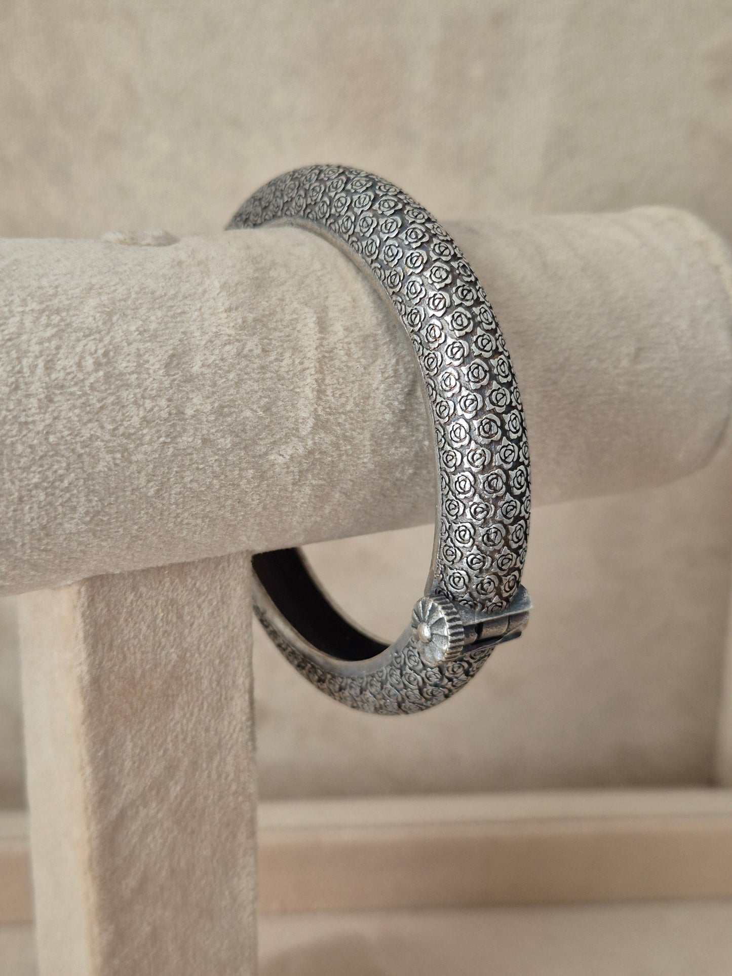 Close-up of Naitri's Harshada silver bangle featuring a textured floral pattern and a hinge clasp by naitri.in