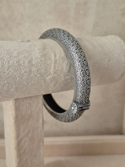 Close-up of Naitri's Harshada silver bangle featuring a textured floral pattern and a hinge clasp by naitri.in