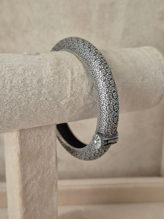Close-up of Naitri's Harshada silver bangle featuring a textured floral pattern and a hinge clasp by naitri.in