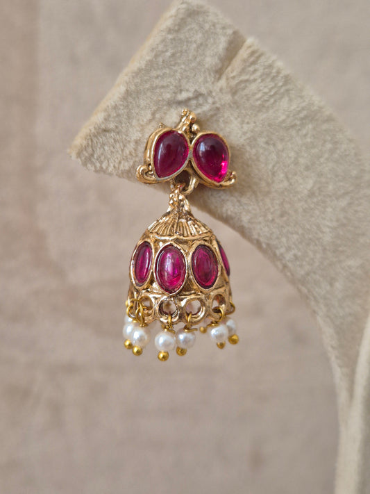 Handcrafted earrings in brass alloy with vibrant pink stones and a polished golden finish, styled white bead accents by naitri.in