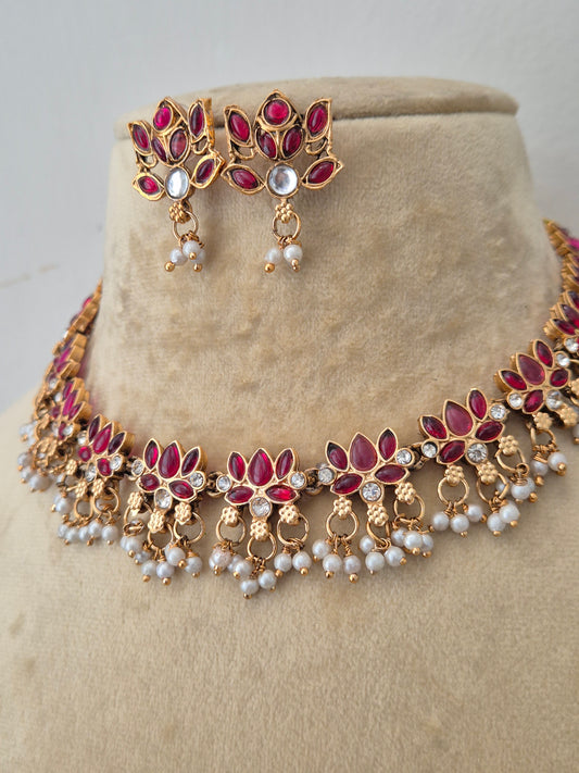 Modern Indian temple-style imitation jewelry set including a golden brass alloy choker necklace embedded with ruby-red stones and white pearls, by naitri.in