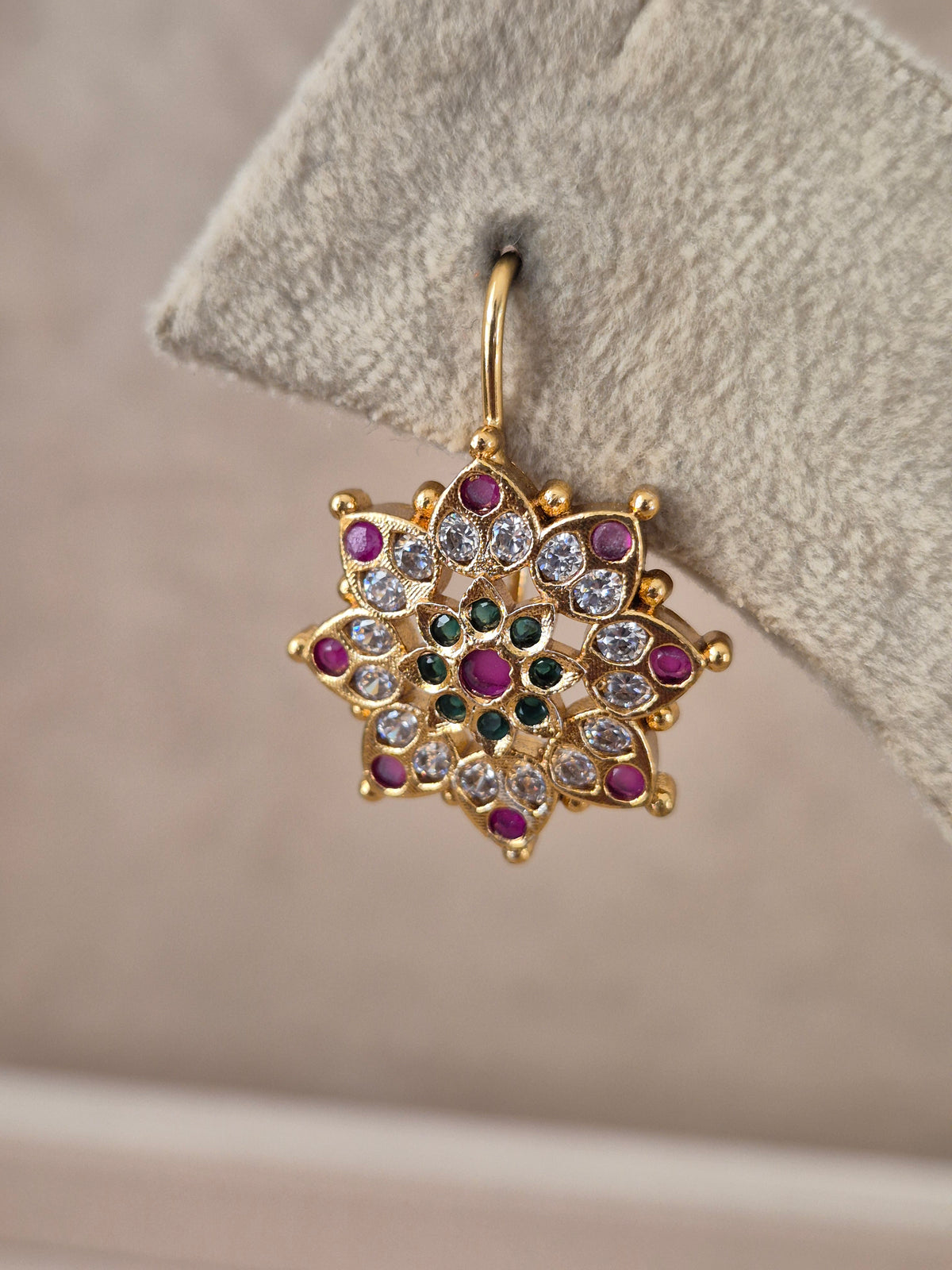 Pair of brass alloy stud earrings featuring a central cluster of vibrant red, green, and white stones arranged in a floral motif by naitri.in