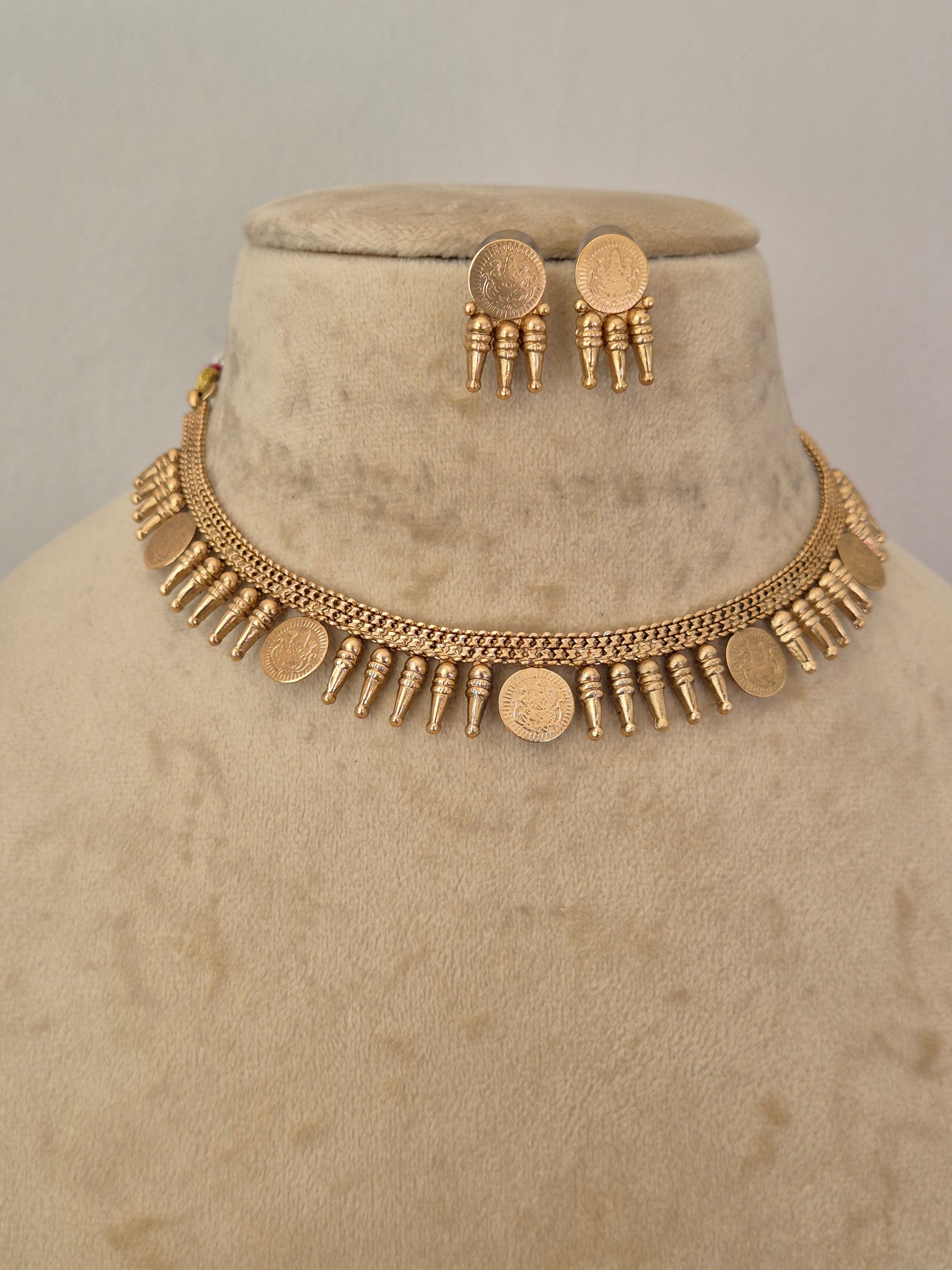 A gold-toned necklace and matching earrings Traditional gold-toned choker necklace with hanging coin elements and matching textured round earrings, by naitri.in