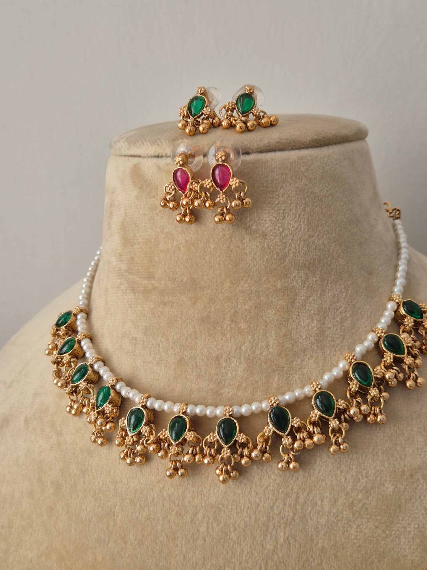 Traditional Indian antique gold-plated brass jewelry set showcasing a dainty pearl collar layout, vibrant green stone charms, and coordinating reversible kemp stone earrings from the Naitri collection by naitri.in
