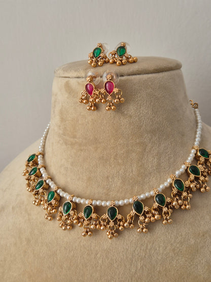 Traditional Indian antique gold-plated brass jewelry set showcasing a dainty pearl collar layout, vibrant green stone charms, and coordinating reversible kemp stone earrings from the Naitri collection by naitri.in