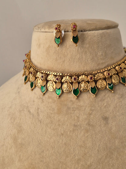 Antique gold-finish choker necklace with intricate metalwork and green teardrop stones, paired with small green stone earrings for a traditional Indian aesthetic by naitri.in