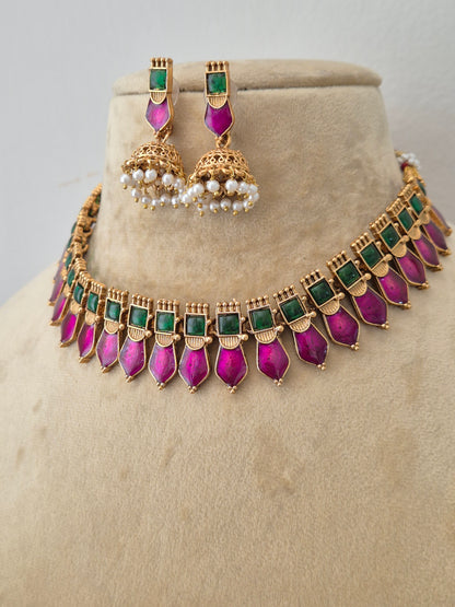 Modern Indian ethnic imitation jewelry set including a golden brass alloy choker necklace embedded with vibrant green and pink stones, shown with matching jhumka earrings featuring white pearl drops by naitri.in