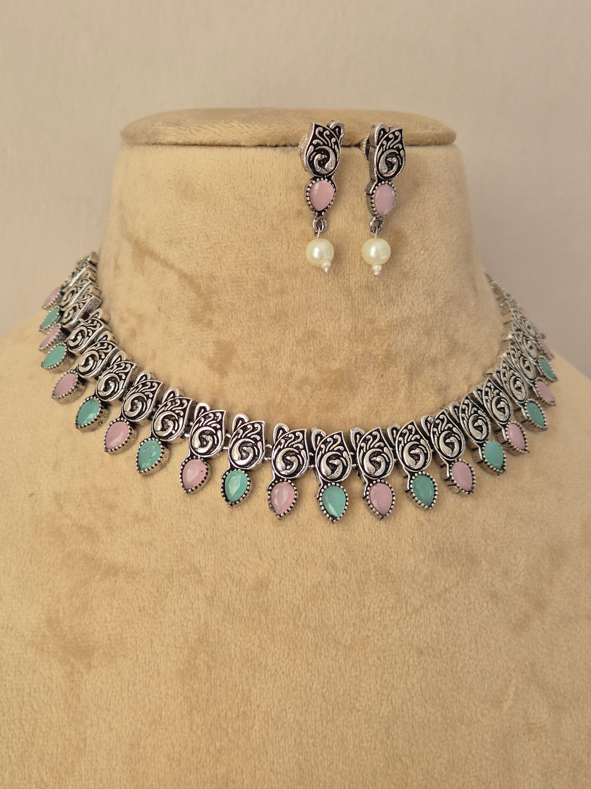Pair of oxidized silver floral motif necklace featuring light blue stones paired with matching drop earrings by naitri.in