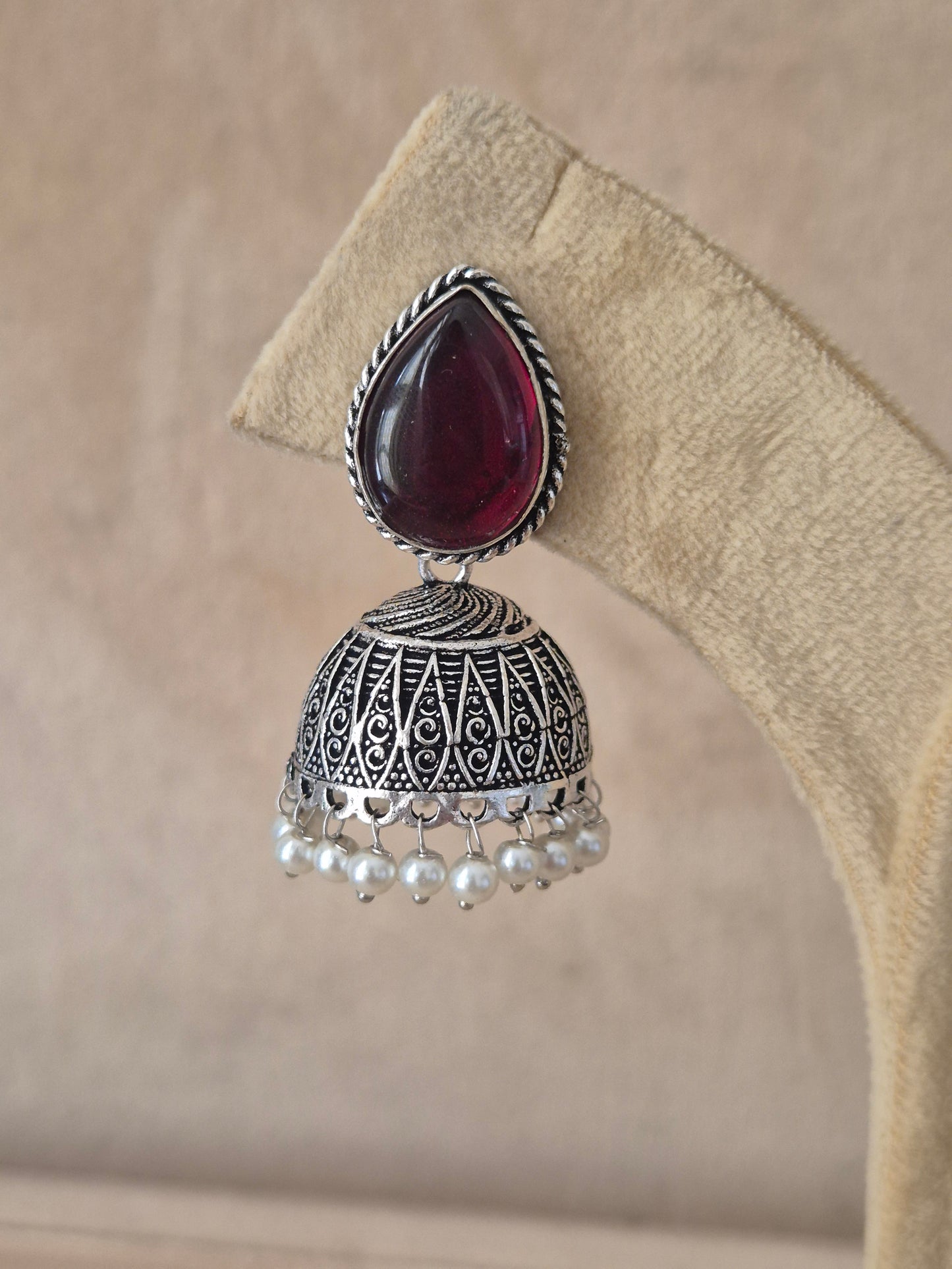 Modern Indian aesthetic silver-plated statement jhumkas featuring a vibrant purple focal stone and intricate metalwork by naitri.in