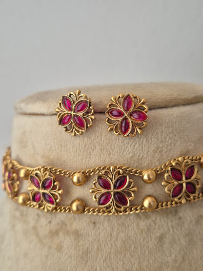 Gold-tone floral jewelry set with magenta-pink stone accents, including a bracelet and matching earrings, Gold-toned floral choker necklace set with pink gemstones and matching stud earrings, by naitri.in