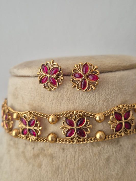 Gold-tone floral jewelry set with magenta-pink stone accents, including a bracelet and matching earrings, Gold-toned floral choker necklace set with pink gemstones and matching stud earrings, by naitri.in