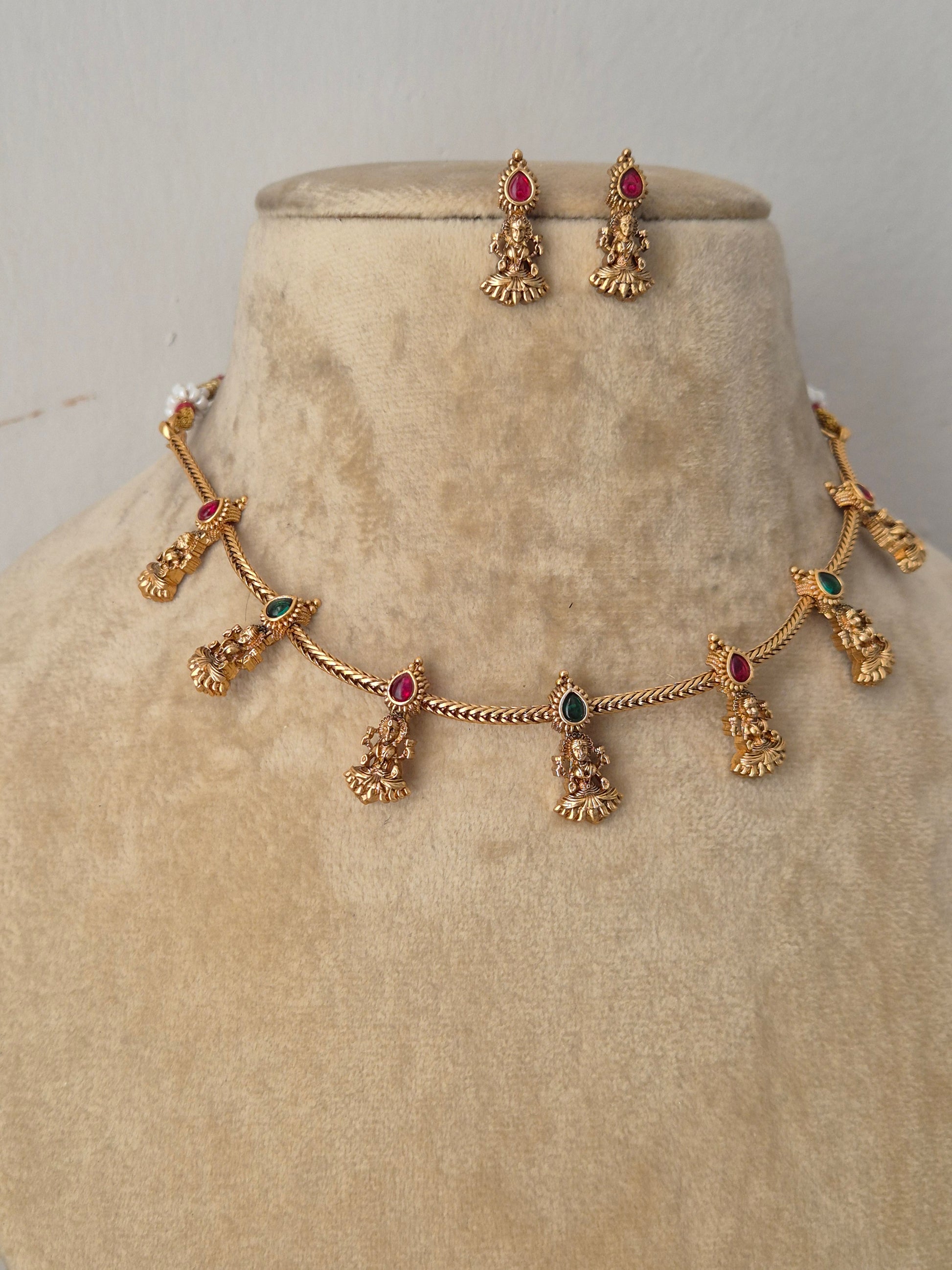 Antique gold-plated ethnic choker set featuring delicate dangling pendants with tiny red- green  stone accents with coordinating hanging stud earrings by naitri.in