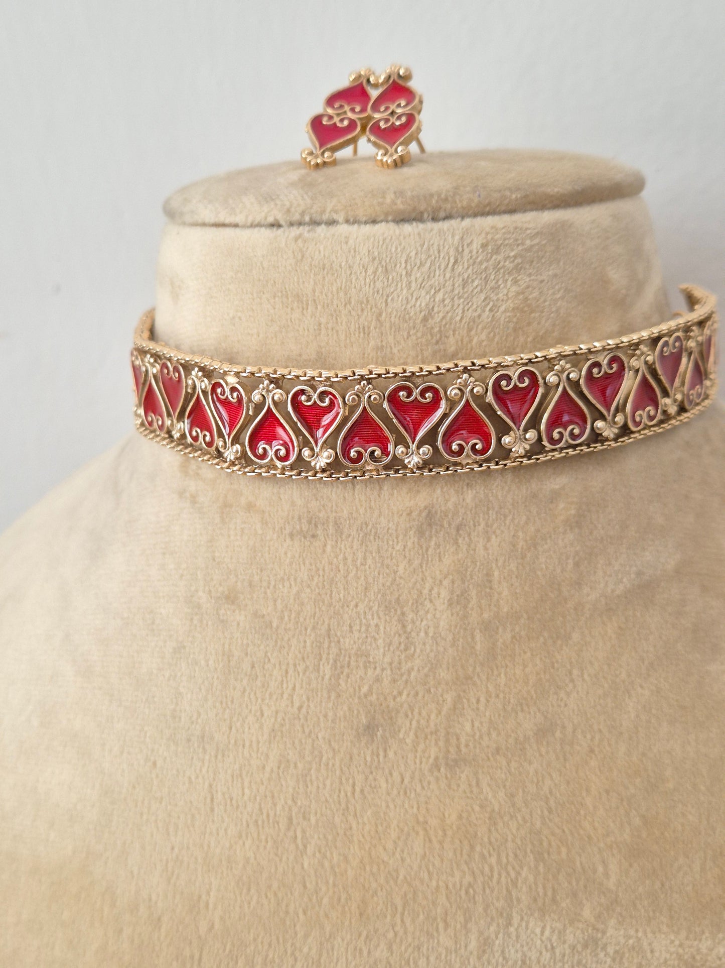 Modern Indian ethnic imitation jewelry set including a golden brass alloy choker necklace with intricate cutouts and vibrant red stone filling by naitri.in