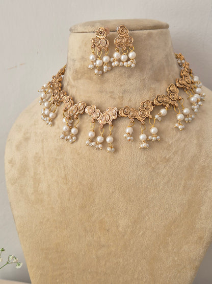 Modern Indian traditional imitation jewelry set including a golden brass alloy choker necklace with delicate floral detailing and cascading white pearl tassels by naitri.in