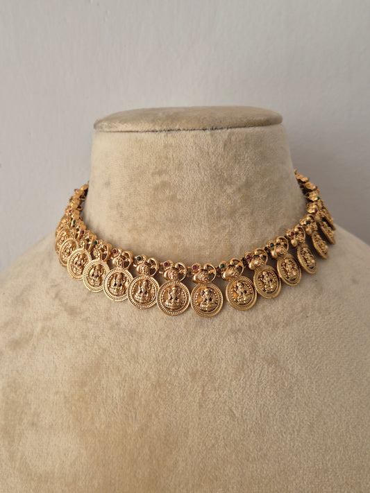 Modern Indian ethnic imitation jewelry set including a golden brass alloy coin choker necklace, shown with matching traditional earrings decorated with a small pinkish-red stone by naitri.in